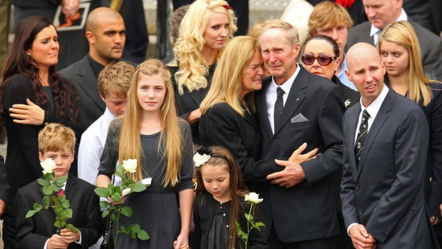 As Jim Stynes' coffin is loaded into the hearse, son Tiernan, daughter Matisse (holding an unidentified child's hand), mother Tess, father Brian snr and brother Brian look on.