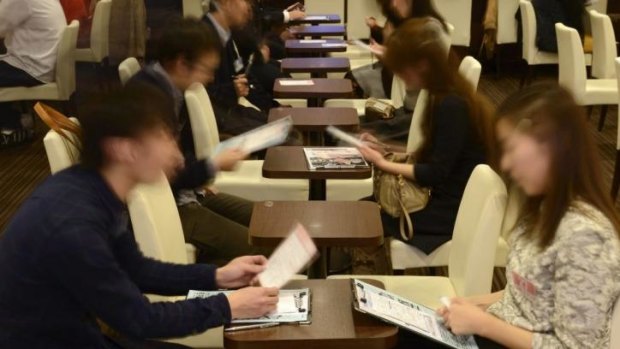 Attendees take notes while talking to each other at a matchmaking party in Tokyo.