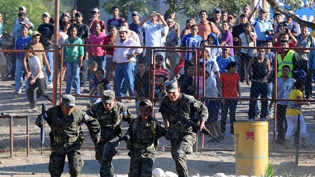 Relatives and friends of inmates waiting outside the perimeter fence throw stones at soldiers and policemen.