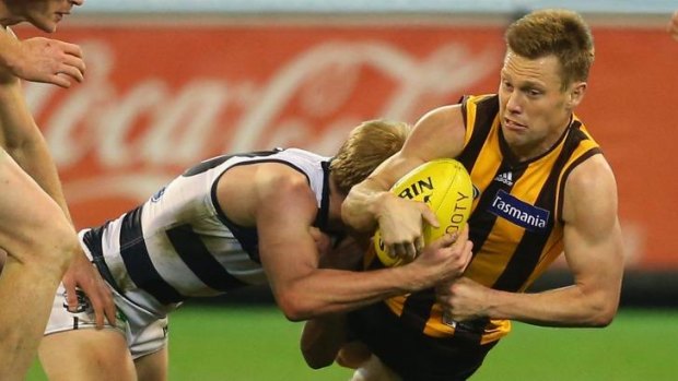 Hawthorn's Sam Mitchell tries to handball as he is held down by Geelong's George Horlin-Smith.