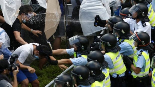 On attack: Riot police use pepper spray as tens of thousands of protesters block the main street to the financial district outside the government headquarters in Hong Kong.