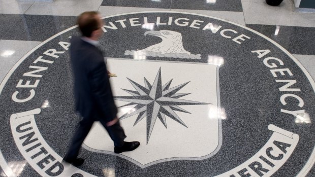 A man crosses the Central Intelligence Agency (CIA) logo in the lobby of CIA Headquarters in Langley, Virginia.