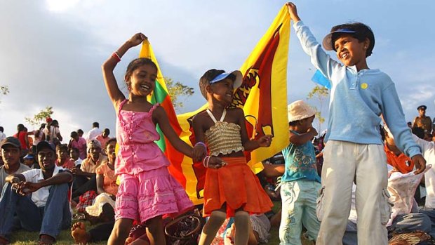 Children wave the Sri Lankan national flag at a cricket international at Hambantota's Mahinda Rajapaksa International Cricket Stadium.