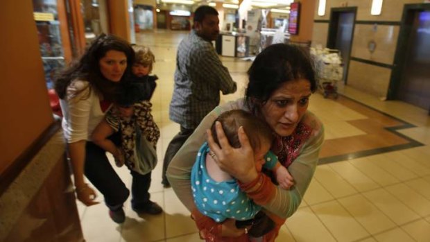 Women carrying children run for safety as armed police hunt gunmen who went on a shooting spree in Westgate shopping centre in Nairobi on September 21.