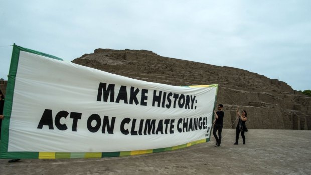 Oxfam members hold a banner at the archaeological site of Huaca Pucllana in Lima.