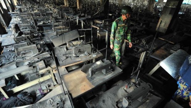 A Bangladeshi soldier walks through rows of burnt sewing machines after the fire in the Tazreen factory.