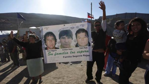 Relatives hold up images of trapped miners.