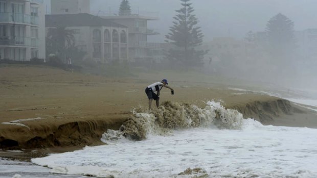 A man takes photographs of the heavy surf at Collaroy Beach in Sydney's northern beaches.