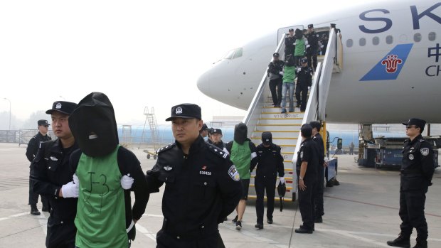 In this photo released by Xinhua News Agency, Chinese suspects involved in wire fraud are escorted off a plane upon arriving at the Beijing Capital International Airport on Wednesday.