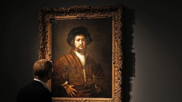 A visitor poses with artist Rembrandt's artwork <i>Portrait of a Man With Arms Akimbo</i> at the Frieze Masters in London.