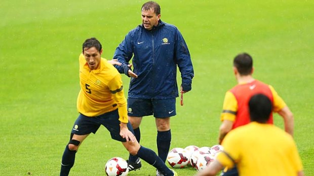 Downpour: Coach Ange Postecoglou battles the weather at Socceroos training on Tuesday.