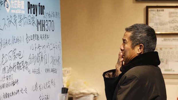 Tears of grief: A relative of a passenger on MH370 cries reading a messageboard at a Beijing hotel.