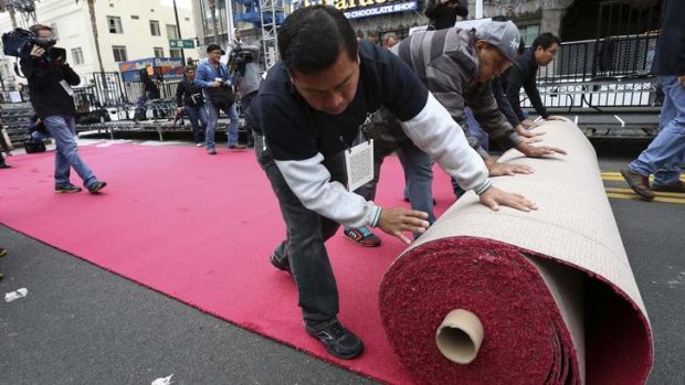Workers roll out the Oscars red carpet during preparations for the 86th Annual Academy Awards in Hollywood.