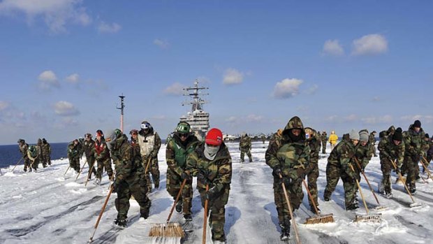 Sailors on the USS Ronald Reagan wash down the flight deck to remove potential radiation contamination.