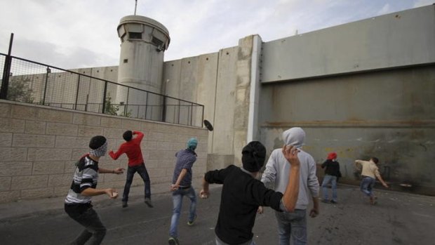 Anger ... Palestinian youths in Bethlehem attack the Israeli security wall with stones on Saturday.