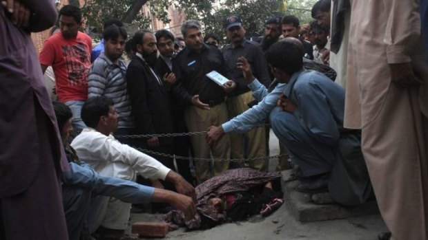 Police collect evidence near the body of Farzana Iqbal, who was killed by family members outside  Lahore High Court for marrying the man she loved.