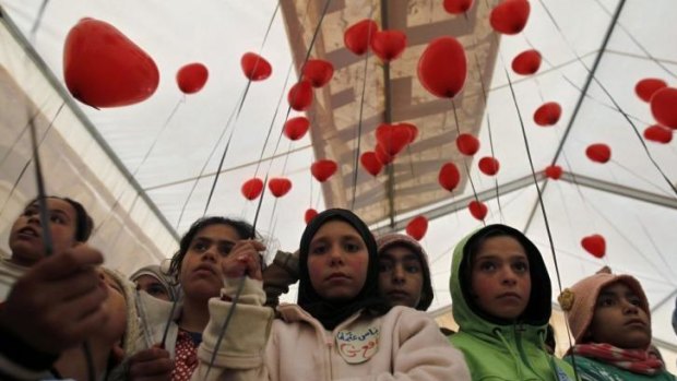 Syrian refugees with red balloons to mark the conflict's third anniversary at the Zaatari refugee camp in Jordan.