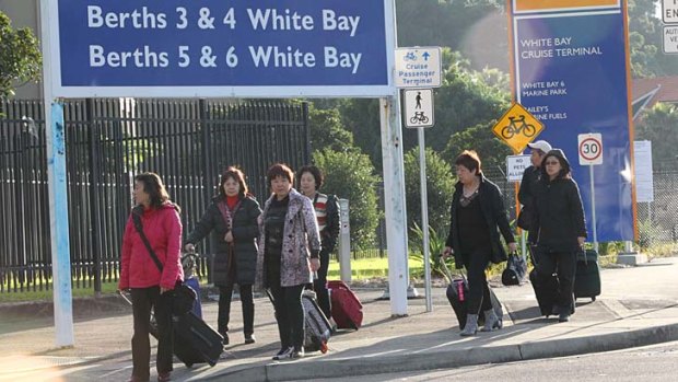 Passengers with luggage walk out of the White Bay terminal.