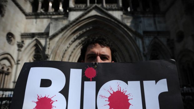 A protester holds a placard bearing the slogan "Bliar" as he demonstrates outside the High Court in central London.