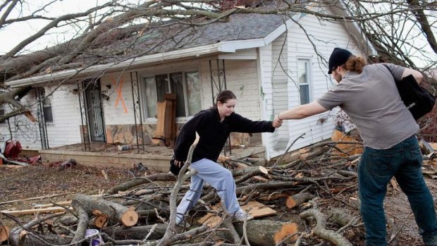Damage ... Harrisburg residents climb over downed limbs as they leave their house.