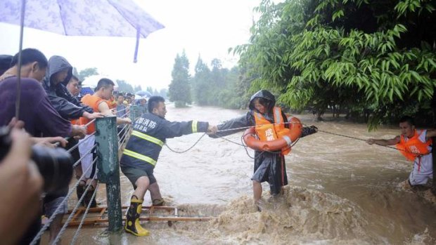 Firefighters use a rope to help a woman walk across floodwaters after heavy rainfalls hit Dujiangyan, Sichuan.