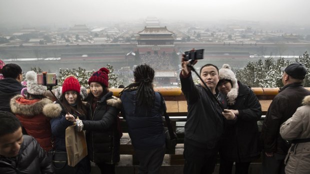 Chinese tourists use 'selfie sticks' to take pictures as they stand on Jingshan Park overlooking the Forbidden City during Spring Festival celebrations in Beijing, China. 