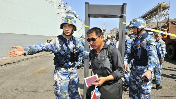 Chinese navy soldiers of the People's Liberation Army (PLA) gesture to Chinese citizens boarding the naval ship Linyi at a port in Aden during their evacuation.