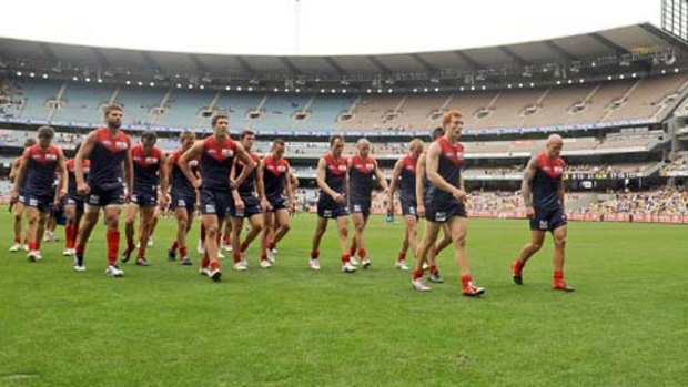 A dejected Melbourne outfits leaves the ground after being hammered by Hawthorn.