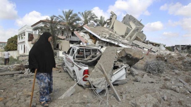 A Palestinian woman walks past the remains of a house which police said was destroyed in an Israeli air strike in Gaza City. At least 184 Palestinians, mainly civilians, have been killed since the offensive began, according to Gaza health officials.