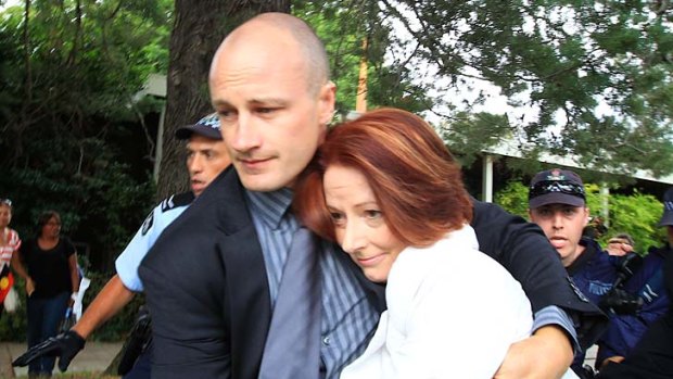 "Visibly rattled" ... Prime Minister Julia Gillard is dragged away by her security detail.