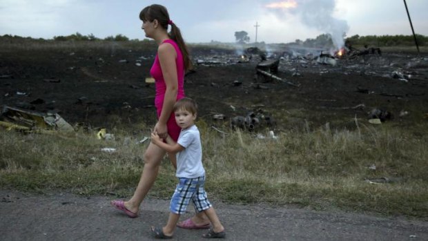 Frightful sight: A woman and child walk past the crash site.