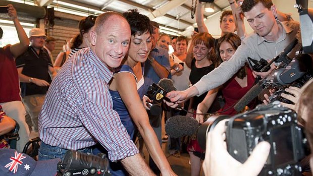 Campbell Newman and wife Lisa fight their way through the media crush to cast their votes in the seat of Ashgrove.