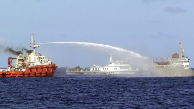 A Chinese ship, left, shoots water cannon at a Vietnamese vessel, right, while a Chinese Coast Guard ship, center, sails alongside in the South China Sea.