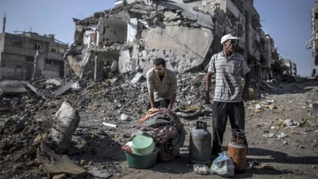 Palestinian men gather things they found in the rubble in the Shejaiya residential district of Gaza as families returned to find their homes destroyed by Israeli tank fire and air strikes. 