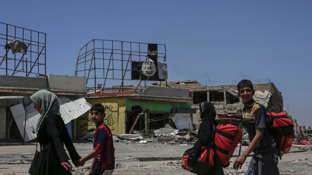 A displaced family passes an Islamic State banner in western Mosul earlier this month.