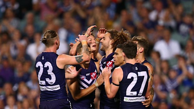 Griffin Logue is congratulated by team mates after kicking a goal against the Roos.