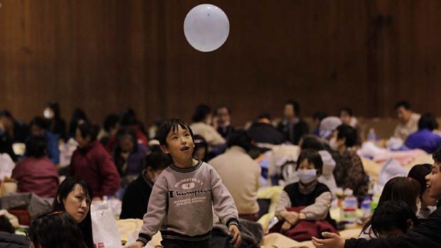 Light moment ...  a boy plays with a balloon at one of the many gyms across Japan being used as shelters.