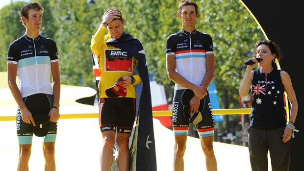 Proud Aussie ... Tina Arena sings the national anthem as Cadel Evans celebrates on the podium, flanked by Andy Schleck, left, and Frank Schleck.