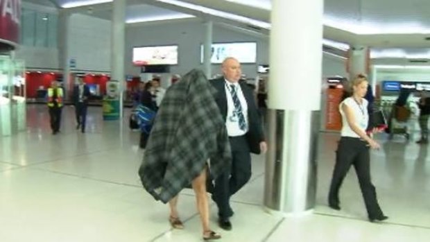 Police escort the accused transgender prostitute from Perth Airport.