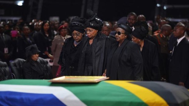 Winnie Madikizela-Mandela, left, Nelson Mandela's former wife, left and Nelson Mandela'?s widow Graca Machel stand over the former president's casket during his funeral service in Qunu, South Africa, Sunday, December 15, 2013.