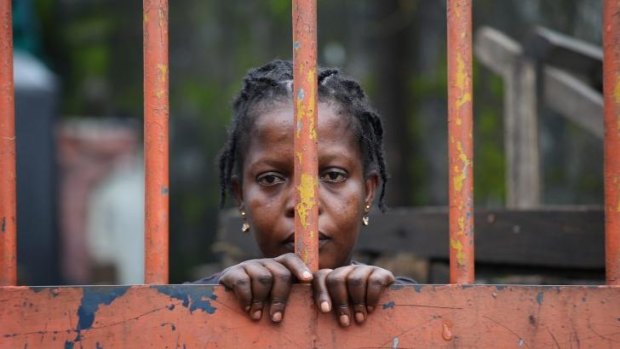 A West Point slum resident looks from behind closed gates on the second day of the government's Ebola quarantine on their neighbourhood.
