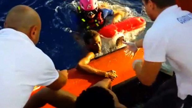 This scene from a video shows rescuers helping a survivor of the capsized immigrant boat to safety off the Italian island of Lampedusa.