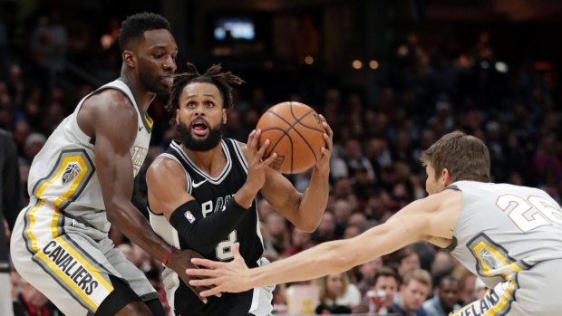 San Antonio Spurs' Patty Mills, center, from Australia, drives between Cleveland Cavaliers' Jeff Green, left, and Kyle Korver in the first half of an NBA basketball game, Sunday, Feb. 25, 2018, in Cleveland. (AP Photo/Tony Dejak)