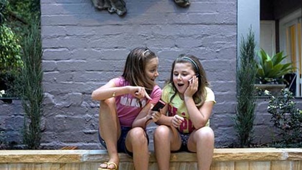 The connected generation . . . Caterina  Kendall-Mandaliti, 9, and Sofia Musarra, 11, using their mobile phones.