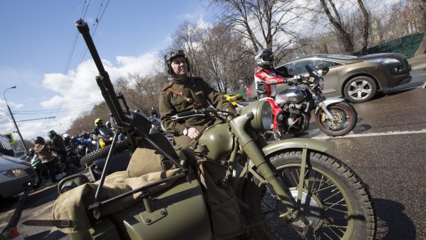 A man wearing a Soviet-era soldier uniform sits in a World War II Soviet army motorcycle to see off Russian bikers leaving for Germany.