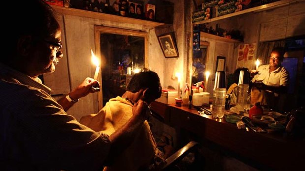 Trying to keep a cut above &#8230; a barber holds a candle while giving a haircut to a customer in Kolkata, India, during the world's biggest blackout which left 600 million people without power for hours.