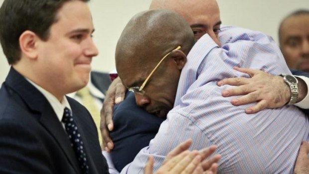 Jonathan Fleming hugs his attorney Anthony Mayol while his other attorney Taylor Koss applauds in Brooklyn's Supreme court, after a judge declared him a free man.