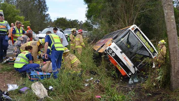 Paramedics treat a patient at the scene of the school bus crash near Port Macquarie.