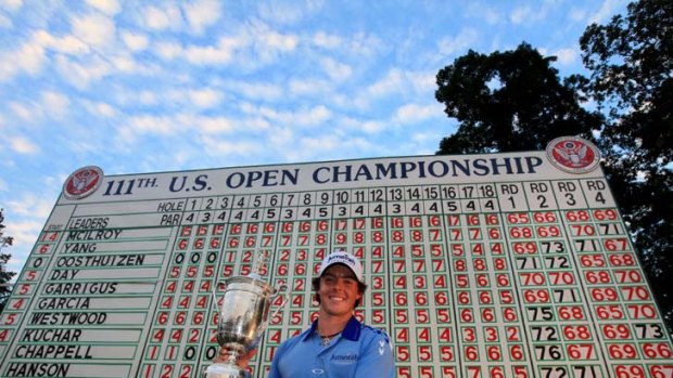 Winning numbers ... McIlroy raises the trophy in front of the US Open scoreboard which breaks down his record-breaking performance at Congressional.