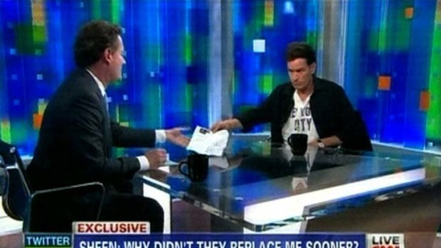 A screen image of Charlie Sheen passing Piers Morgan a document showing how he has been drug free.